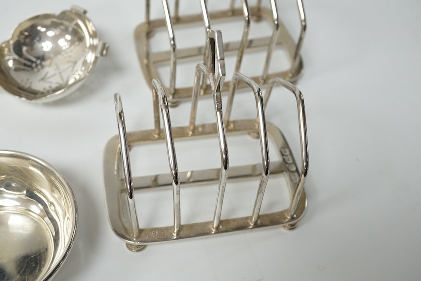 A pair of George V/VI silver five bar toast racks by Hukin & Heath, Birmingham, 1935/39, length 89mm, together with a silver tea strainer and stand, Sheffield, 1958, 9.1oz. Condition - fair to good